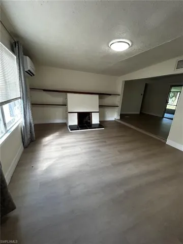 Unfurnished living room with an AC wall unit, a textured ceiling, and a multi sided fireplace