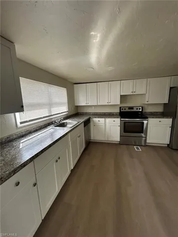 Kitchen with dark wood-type flooring, white cabinets, and stainless steel appliances