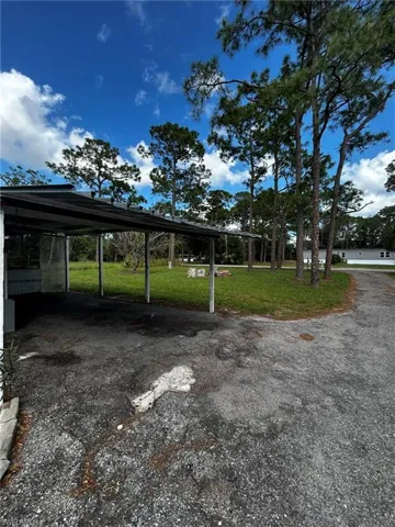 View of parking featuring a yard and a carport