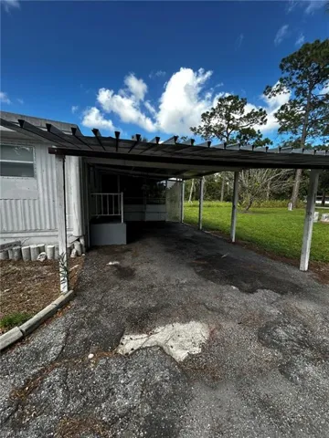 View of car parking featuring a yard and a carport