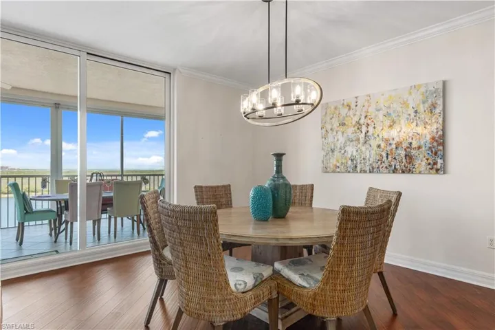 Dining space with a chandelier, baseboards, wood finished floors, and ornamental molding