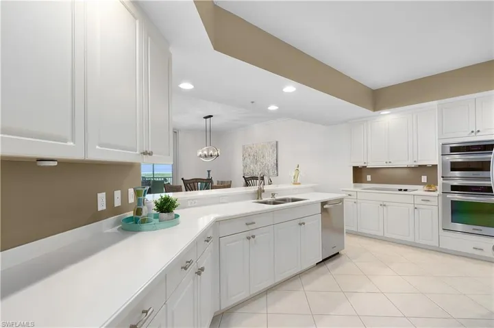 Kitchen with appliances with stainless steel finishes, a sink, light countertops, recessed lighting, and white cabinets