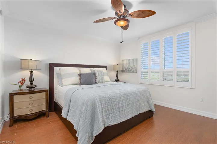 Bedroom with wood finished floors, baseboards, ornamental molding, and a ceiling fan