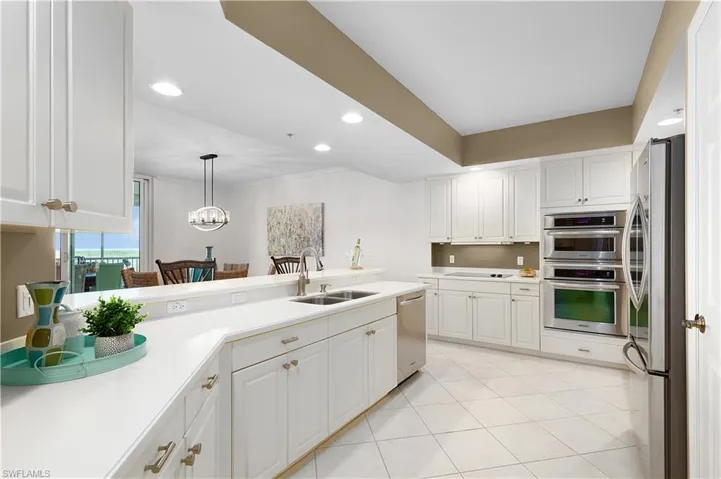 Kitchen with stainless steel appliances, a sink, light countertops, white cabinetry, and recessed lighting