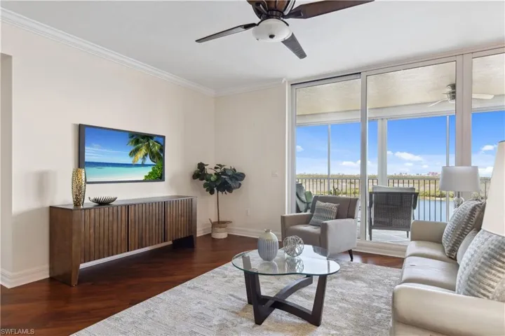 Living room featuring ceiling fan, baseboards, wood finished floors, and crown molding