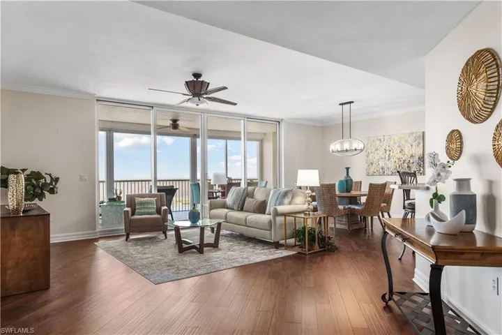Living area featuring ceiling fan, dark wood finished floors, baseboards, a chandelier, and ornamental molding