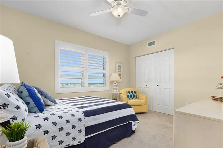 Bedroom with light colored carpet, a closet, and a ceiling fan