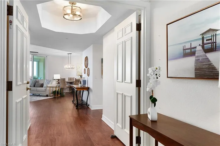 Foyer entrance featuring a chandelier, dark wood-style floors, and baseboards