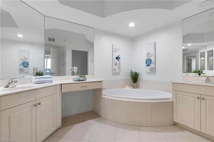 Bathroom featuring a garden tub, tile patterned flooring, recessed lighting, and two vanities