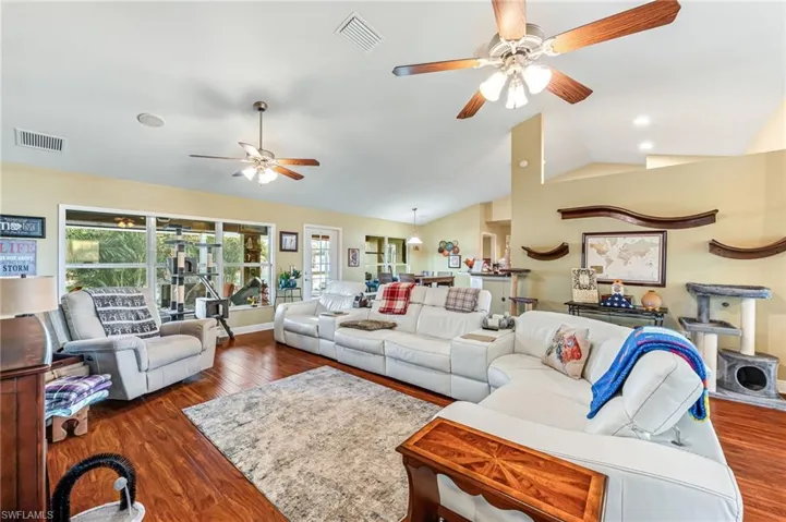 Living room featuring ceiling fan, dark hardwood / wood-style flooring, and lofted ceiling