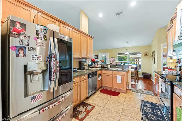 Kitchen with kitchen peninsula, appliances with stainless steel finishes, sink, decorative light fixtures, and light tile patterned flooring
