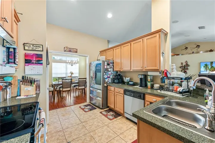 Kitchen featuring sink, a notable chandelier, lofted ceiling, light tile patterned floors, and appliances with stainless steel finishes