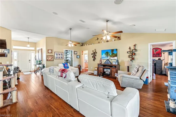 Living room with vaulted ceiling, a wealth of natural light, ceiling fan, and dark hardwood / wood-style floors
