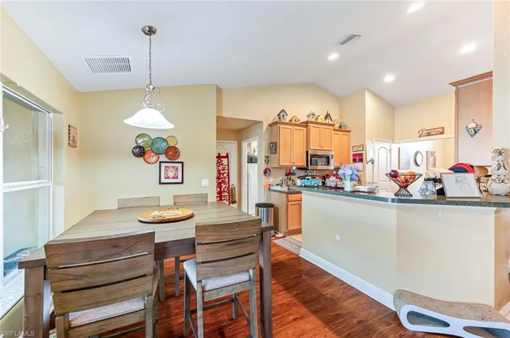 Kitchen featuring vaulted ceiling, kitchen peninsula, hanging light fixtures, and dark hardwood / wood-style floors