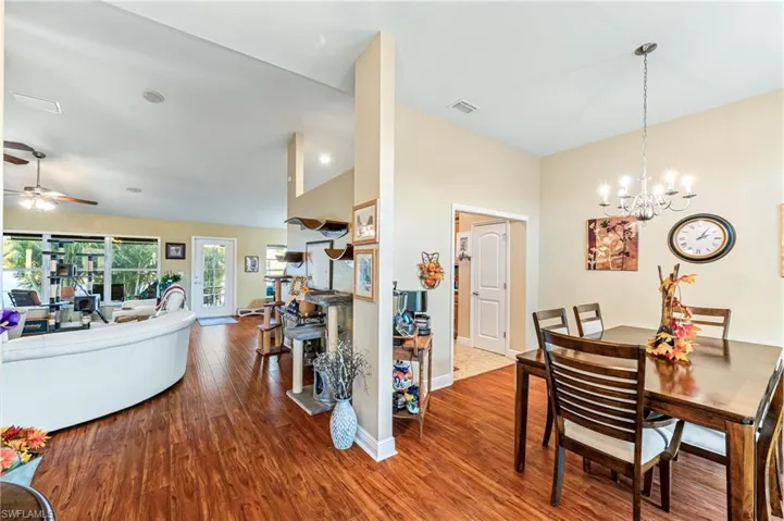 Dining room featuring hardwood / wood-style flooring, ceiling fan with notable chandelier, and lofted ceiling