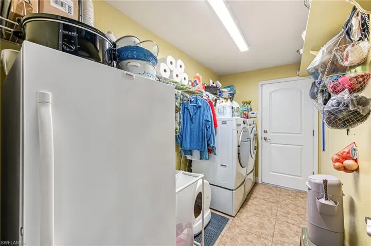 Washroom featuring light tile patterned floors and washing machine and clothes dryer