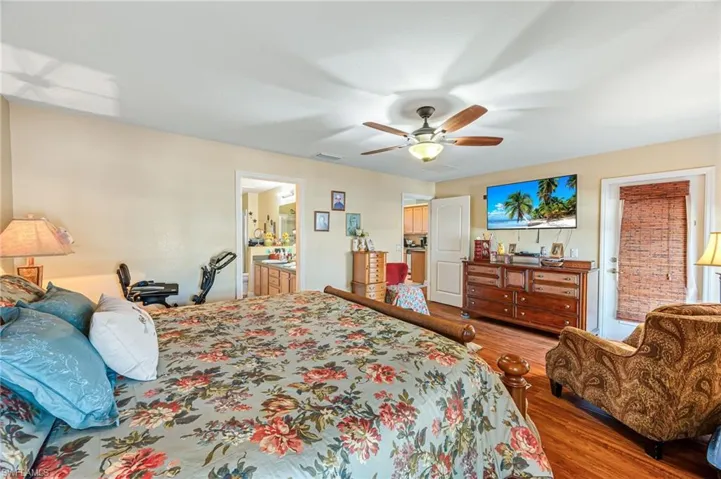 Bedroom featuring hardwood / wood-style floors, ensuite bath, and ceiling fan
