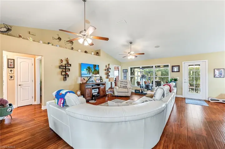 Living room featuring hardwood / wood-style flooring, ceiling fan, and vaulted ceiling