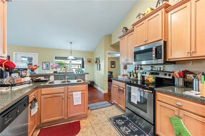 Kitchen featuring sink, lofted ceiling, stainless steel appliances, and light tile patterned floors
