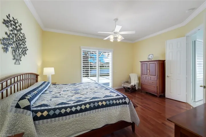Bedroom with crown molding, ceiling fan, and dark hardwood / wood-style flooring