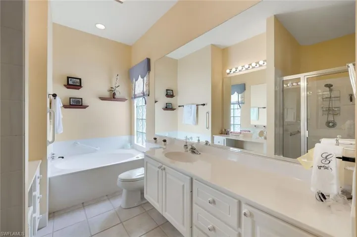 Full bathroom featuring toilet, shower with separate bathtub, vanity, and tile patterned flooring