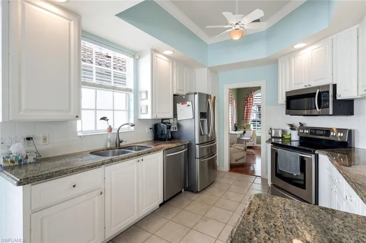 Kitchen featuring white cabinets, light tile patterned floors, appliances with stainless steel finishes, ornamental molding, and sink