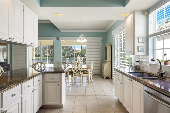 Kitchen featuring sink, dishwasher, hanging light fixtures, white cabinetry, and dark stone countertops