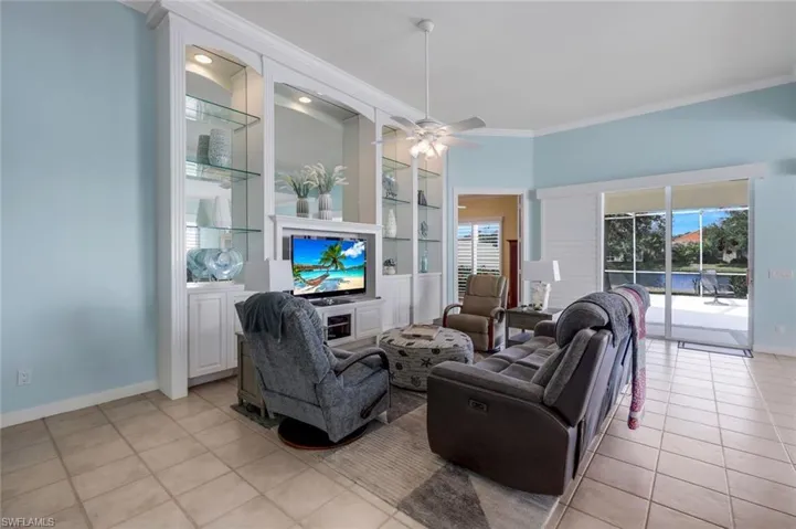 Tiled living room featuring ceiling fan and ornamental molding