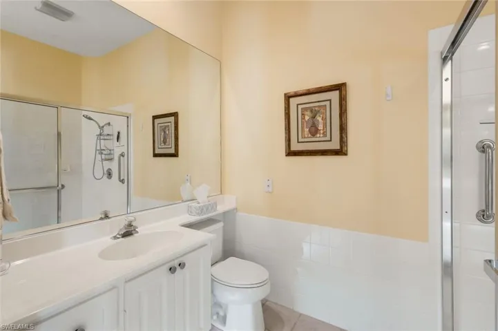 Bathroom with vanity, toilet, tile patterned flooring, and an enclosed shower