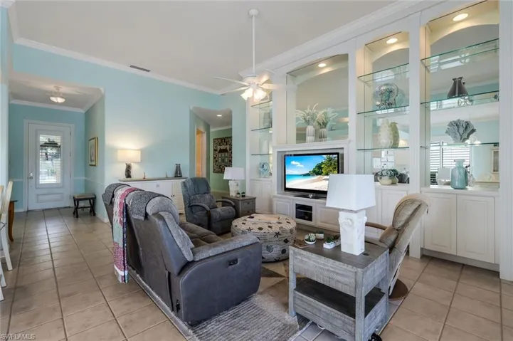 Tiled living room with ornamental molding and ceiling fan