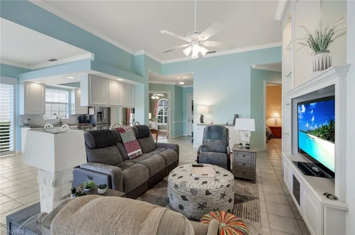 Living room with ornamental molding, ceiling fan, and light tile patterned floors