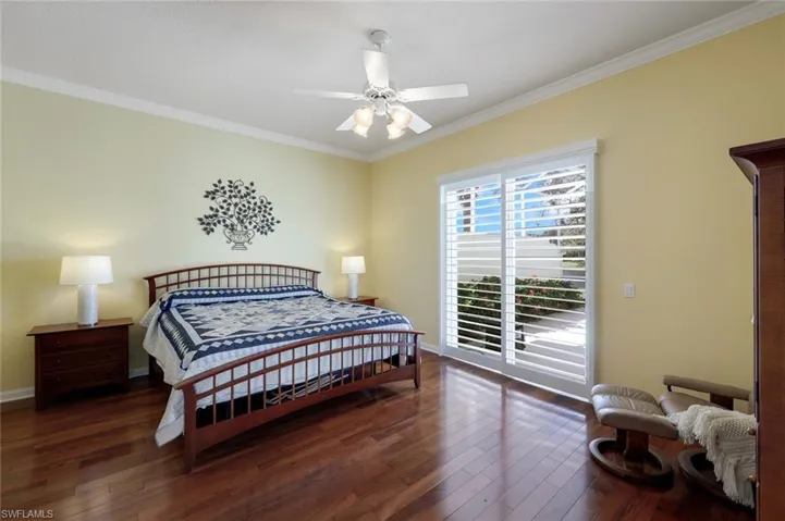 Bedroom with dark wood-type flooring, ceiling fan, crown molding, and access to exterior