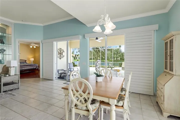 Tiled dining area with ornamental molding and ceiling fan with notable chandelier