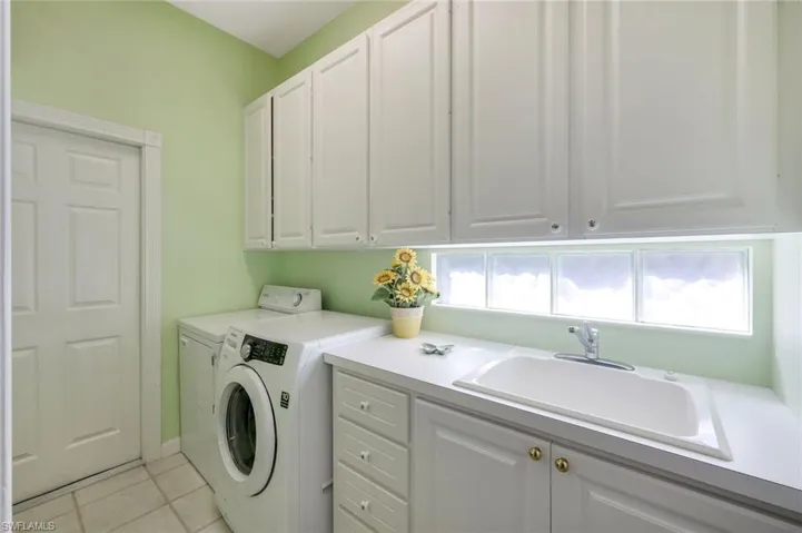 Laundry area with light tile patterned flooring, cabinets, plenty of natural light, and washer and clothes dryer