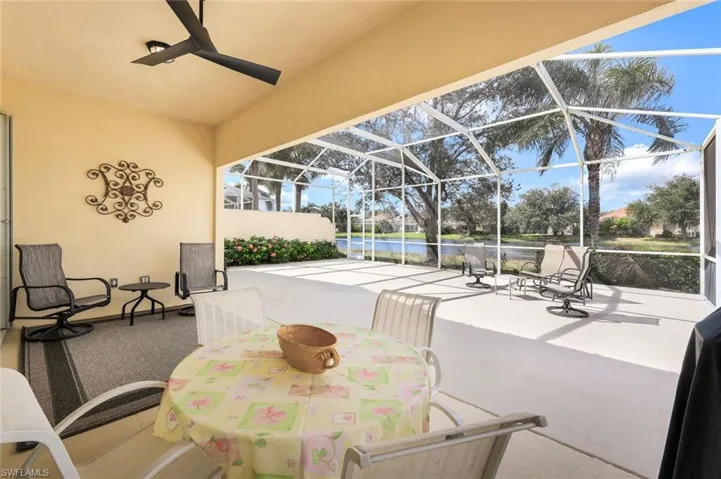 View of patio / terrace featuring a water view, glass enclosure, and ceiling fan
