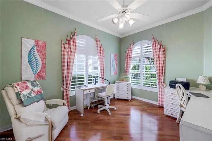 Home office featuring dark wood-type flooring, ceiling fan, and crown molding
