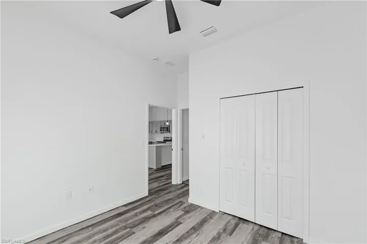 Spacious room featuring wood-finish flooring, a contemporary ceiling fan, and bi-fold closet doors