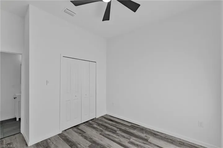 Room featuring wood-finish flooring, a bi-fold closet, and a ceiling fan