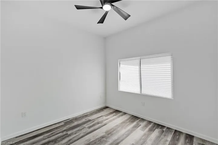 Interior room featuring wood-finish flooring, white walls, and a contemporary ceiling fan