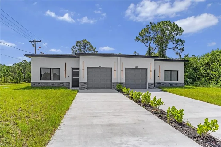 Contemporary duplex featuring a light-colored stucco exterior with dark gray stone veneer accents