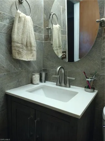 bathroom featuring vanity and tile walls