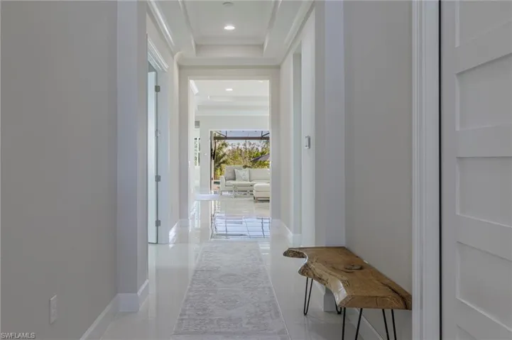 Corridor with light tile patterned flooring and a tray ceiling