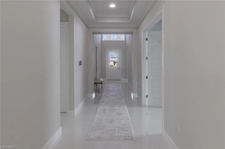 Corridor featuring light tile patterned floors and a tray ceiling