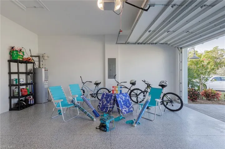 Garage featuring electric water heater, electric panel, and a garage door opener