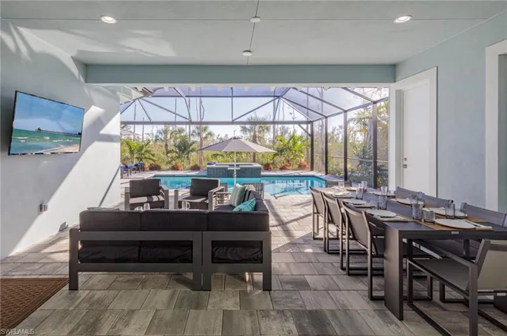 View of pool featuring glass enclosure, an outdoor living space, and a patio