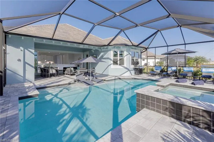 View of pool with an in ground hot tub, a patio, and glass enclosure