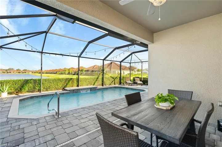 View of swimming pool featuring a water view, ceiling fan, a lanai, and a patio area