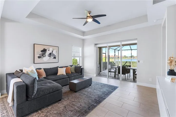 Living room with a water view, ceiling fan, and a tray ceiling