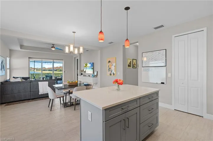 Kitchen with ceiling fan with notable chandelier, a center island, pendant lighting, and gray cabinetry
