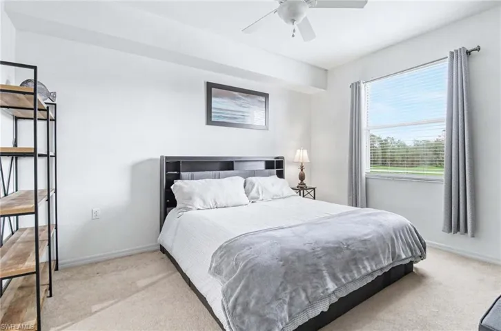 Spacious Primary bedroom with lighted ceiling fan and tranquil lake, golf course and preserve views.